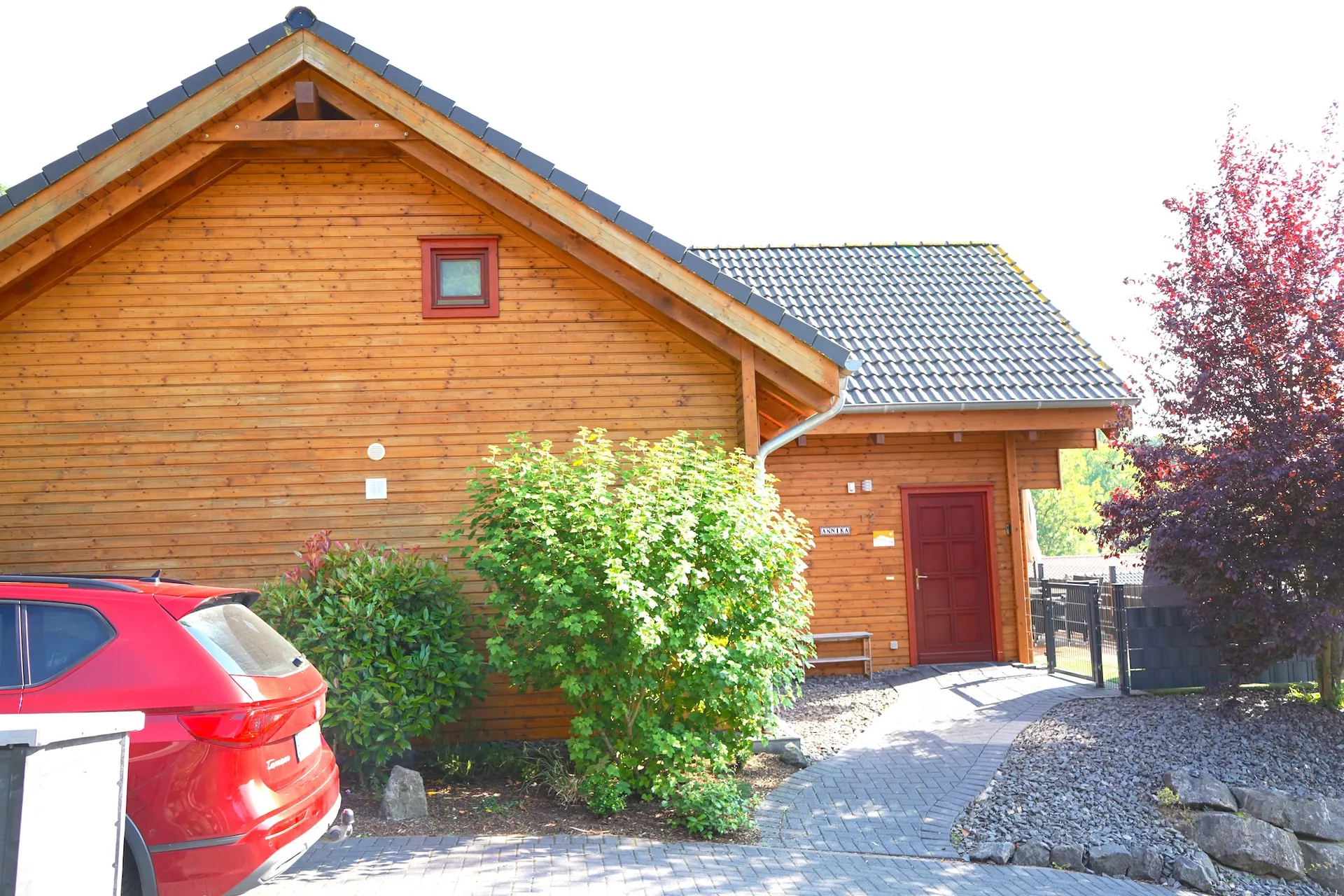 Ferienhaus Annika im Sommer: Holzhaus mit roter Haustür und Vorplatz
