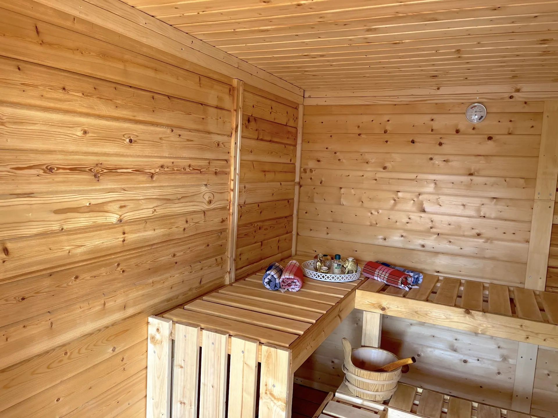 Inside the outdoor sauna at Holiday Home Annika with wooden benches and an infusion bucket