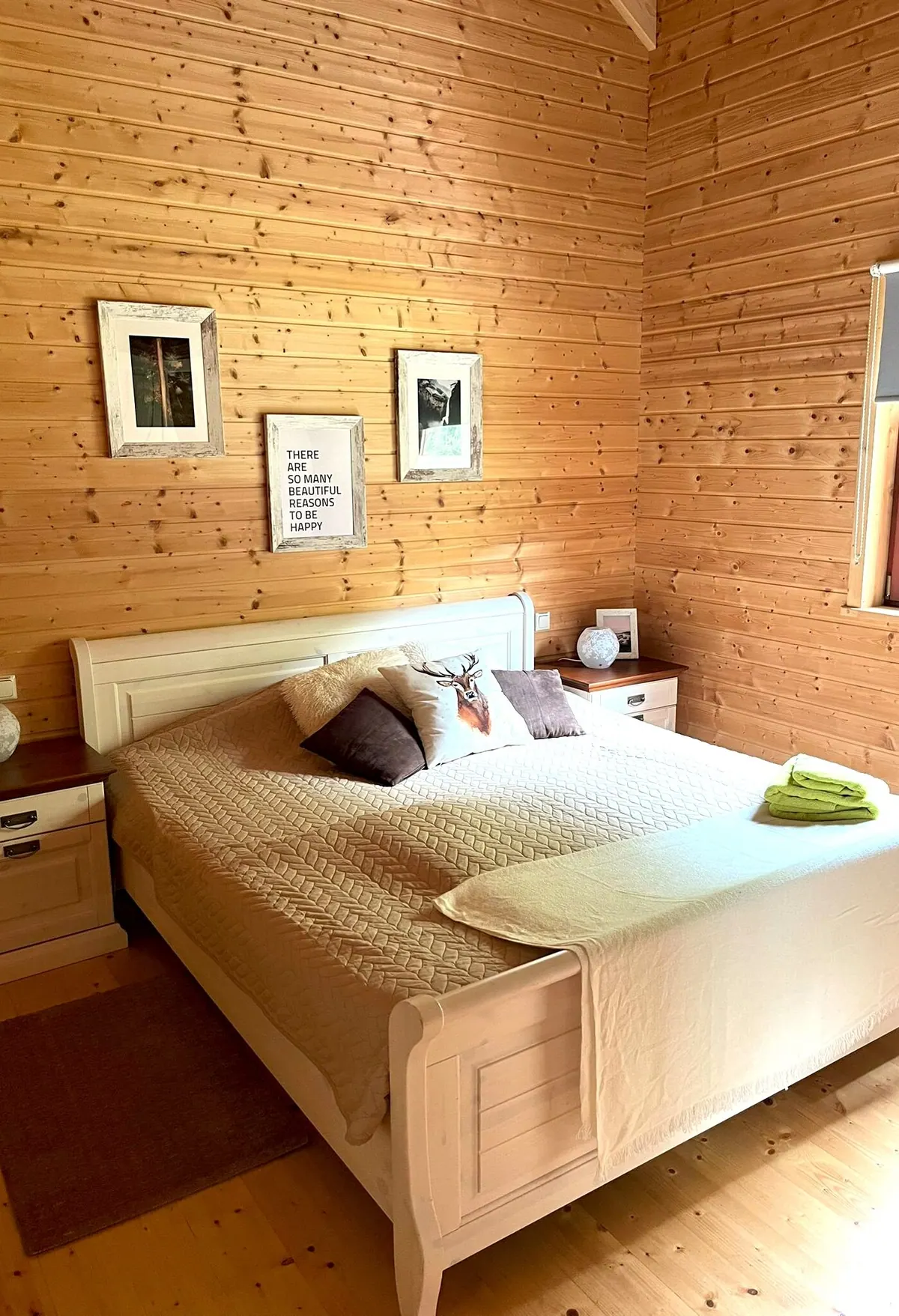 Schlafzimmer im Ferienhaus Annika mit Doppelbett und Bildergalerie an der Holzwand