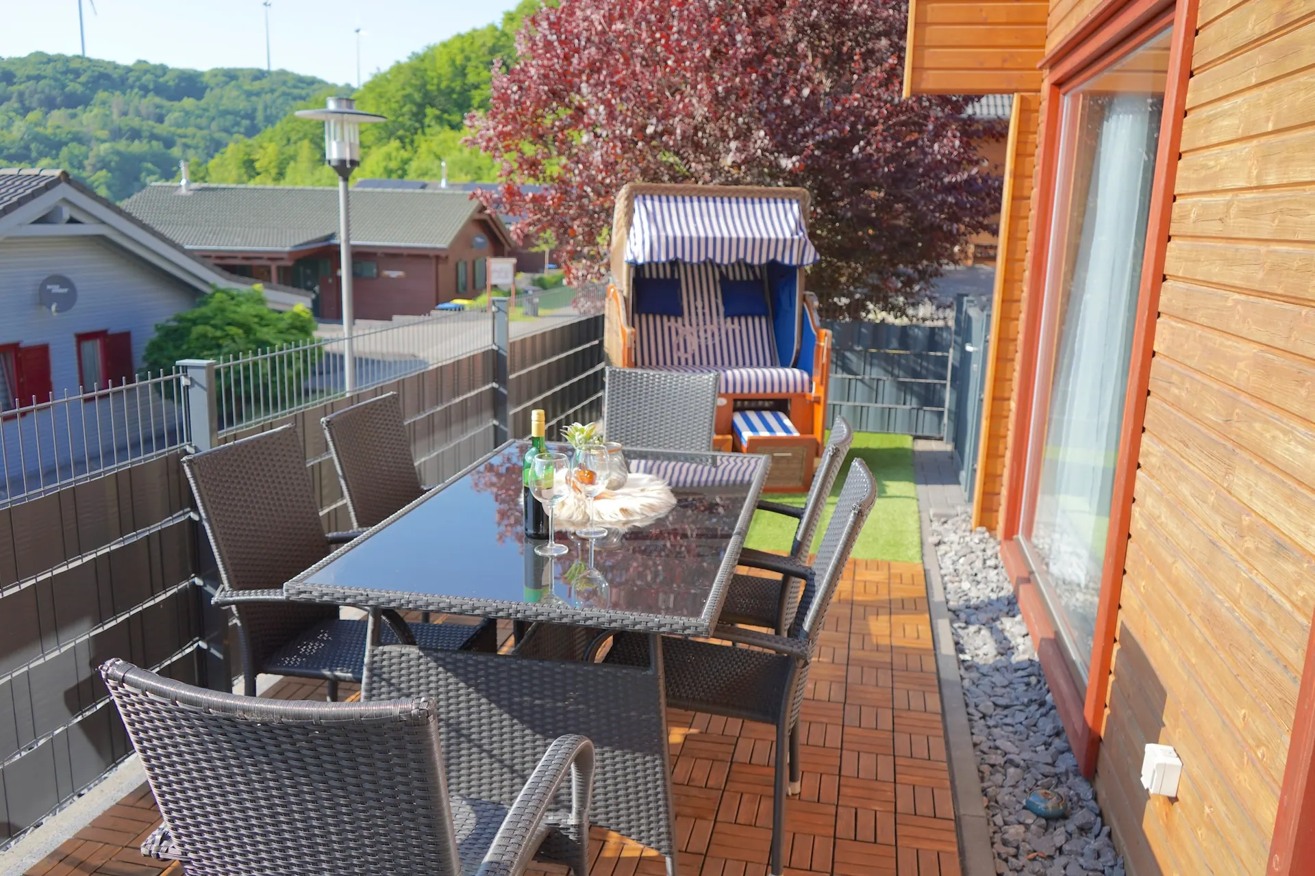 Terrasse vom Ferienhaus Annika mit Esstisch, Sitzgruppe und blau gestreiftem Strandkorb