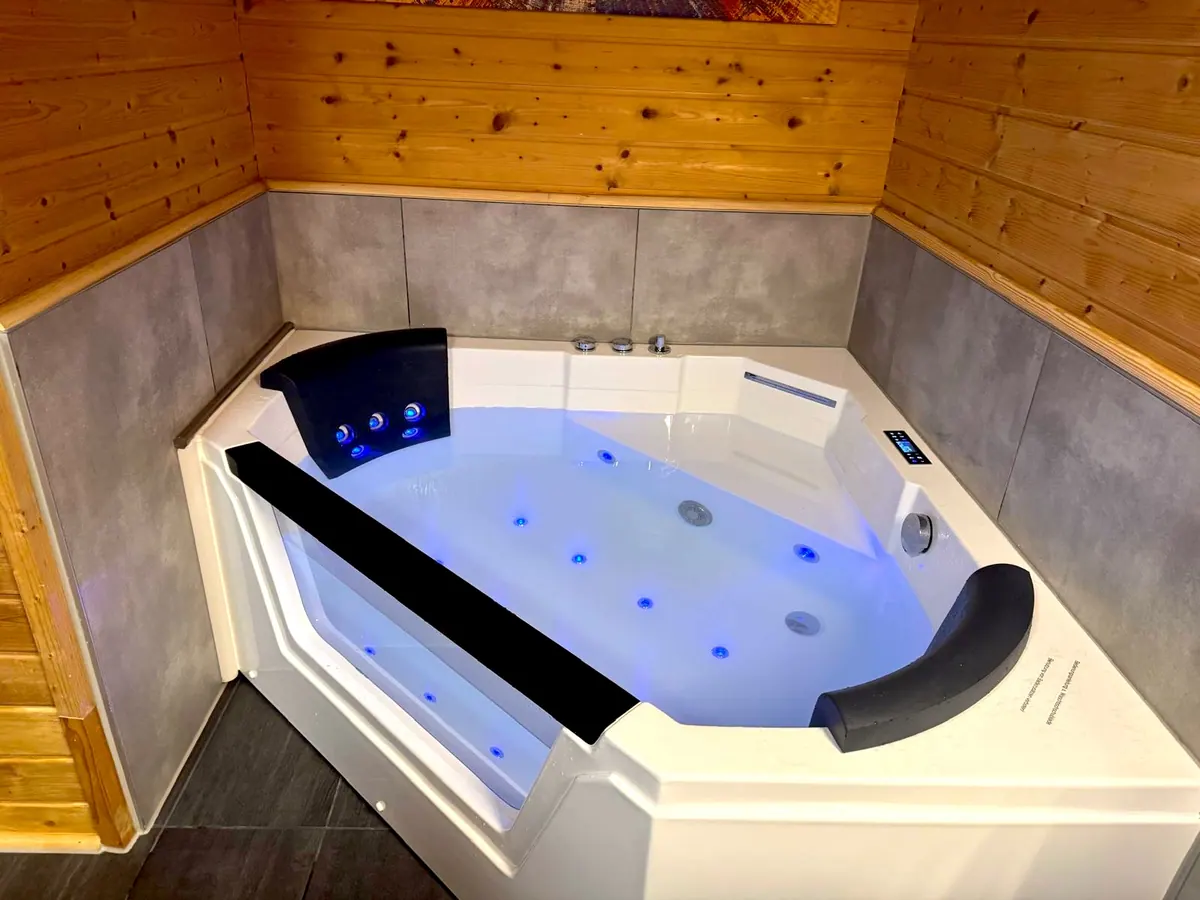 Illuminated luxury whirlpool bath in the bathroom at Holiday Home Annika