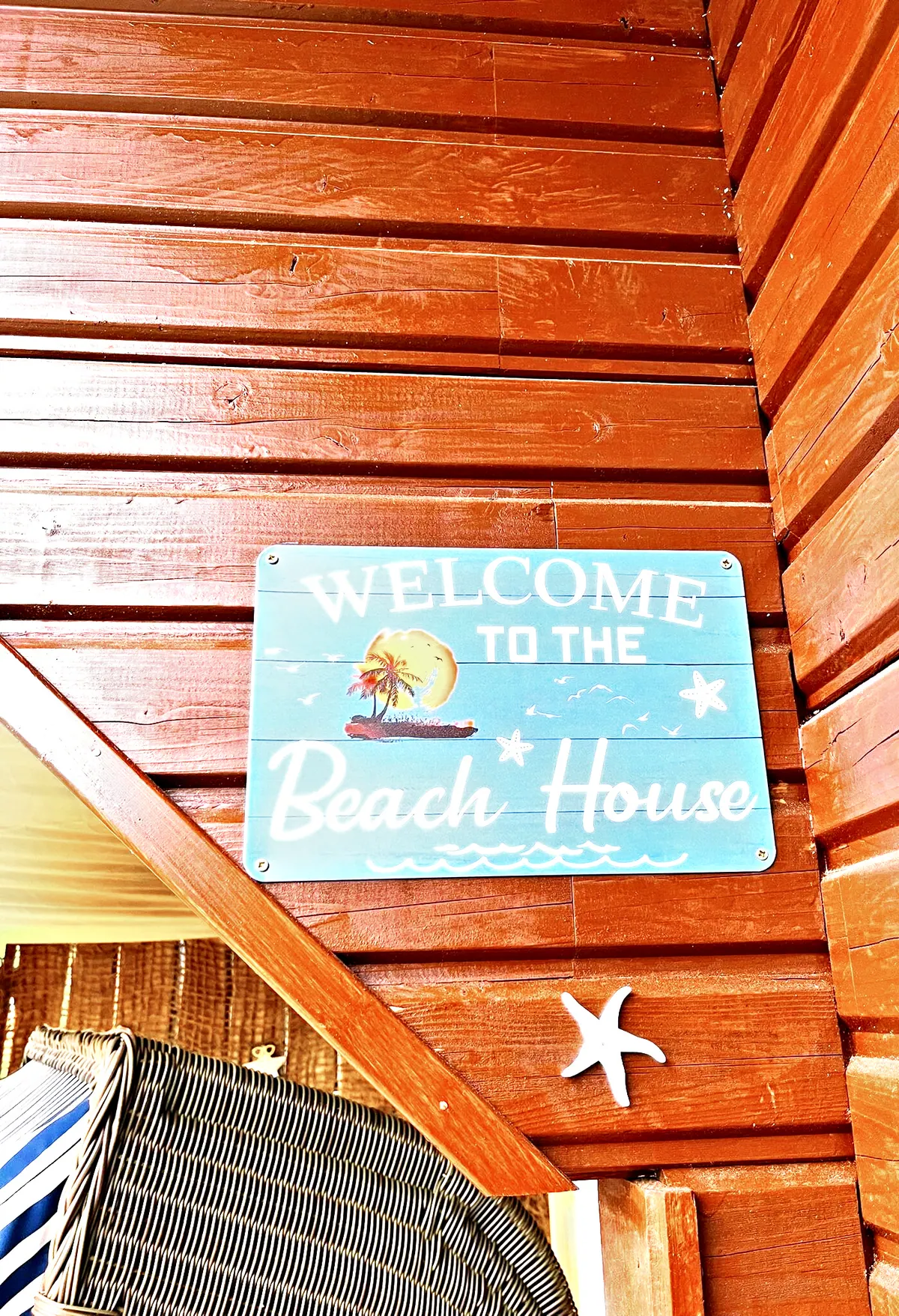 Schild "Welcome to the Beach House" an der Holzwand