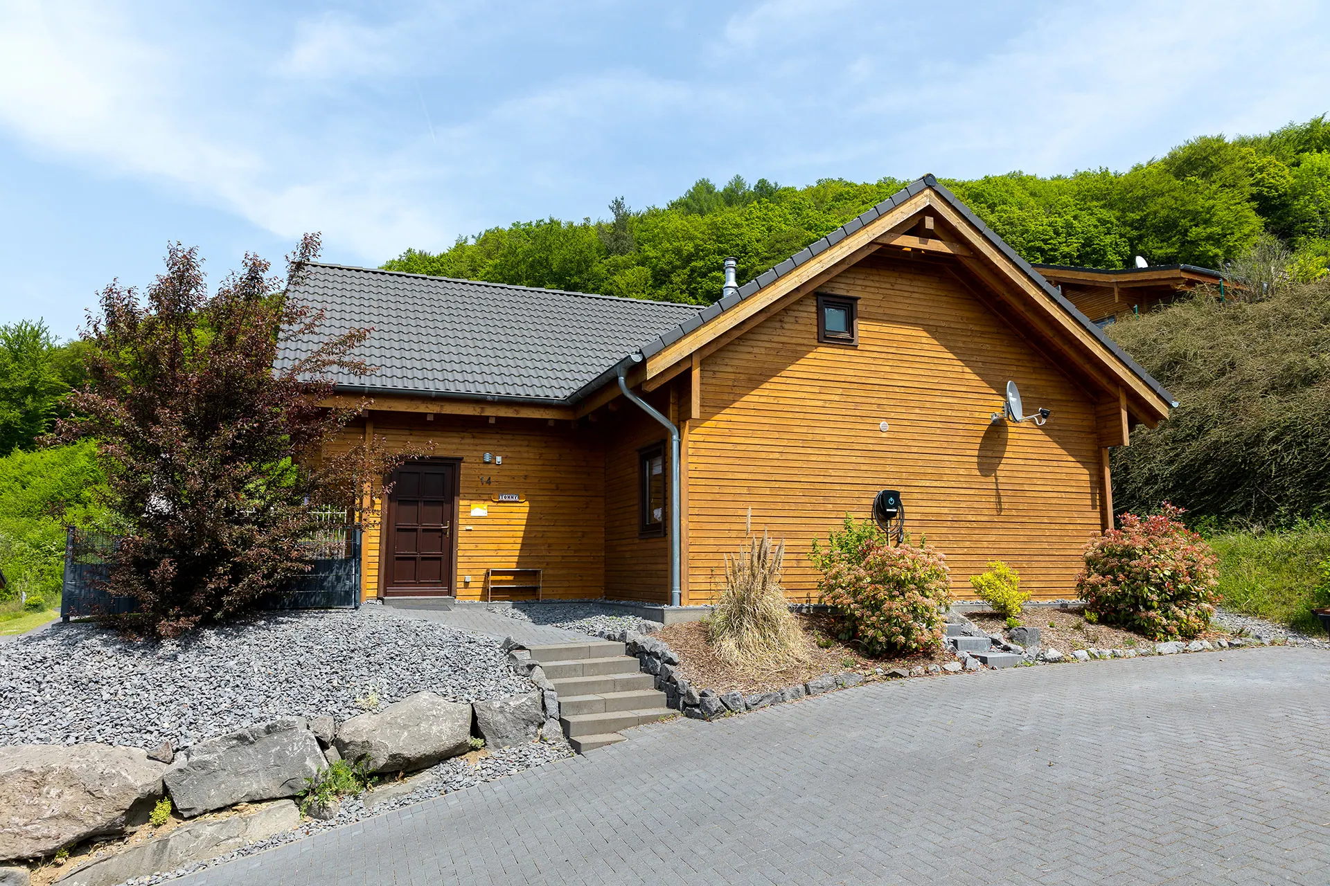 Ferienhaus Tommy von außen: Holzchalet mit überdachter Terrasse und grünen Fensterläden