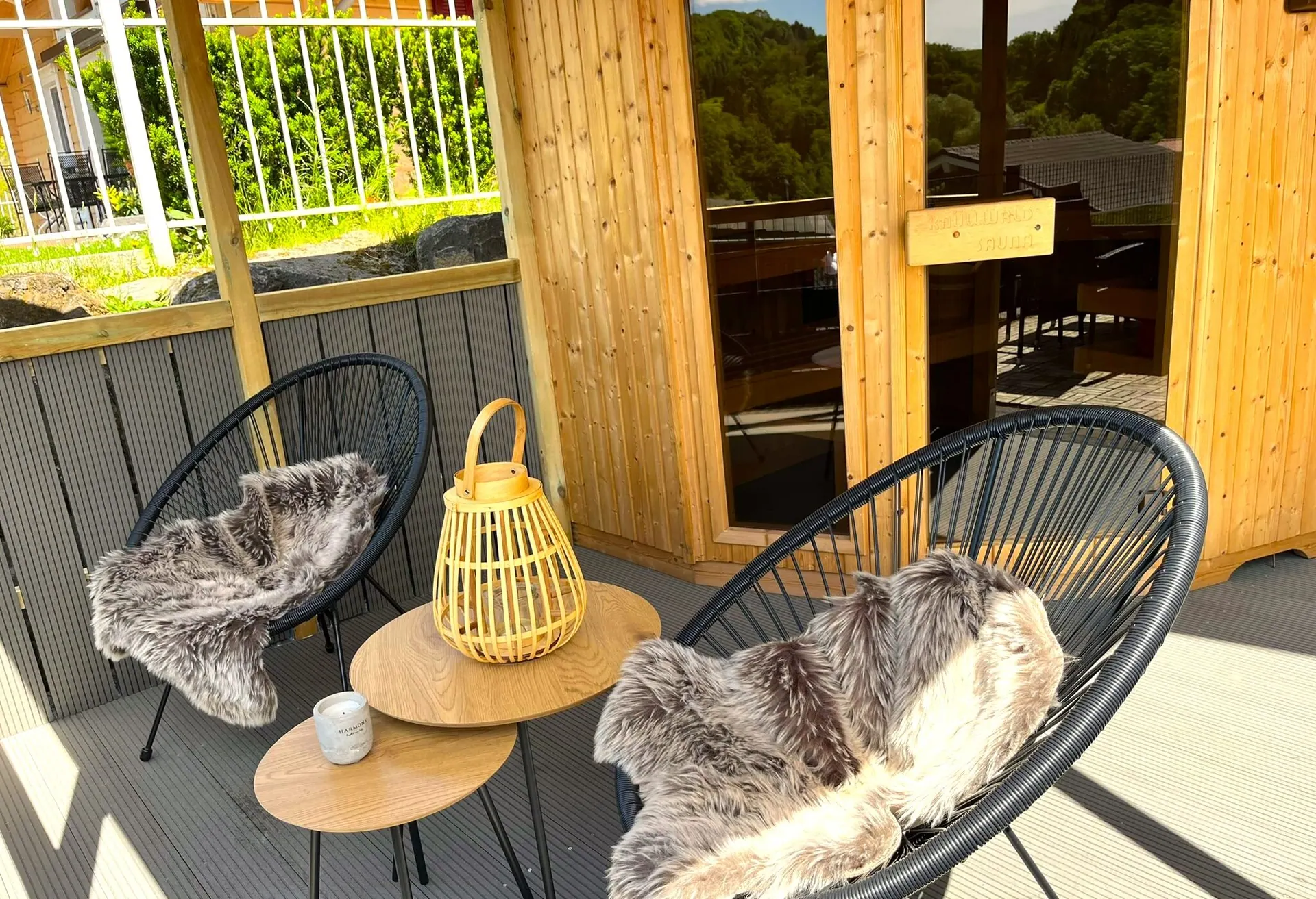 Loungebereich vor der Sauna mit Korbsessel, Laterne und Hund